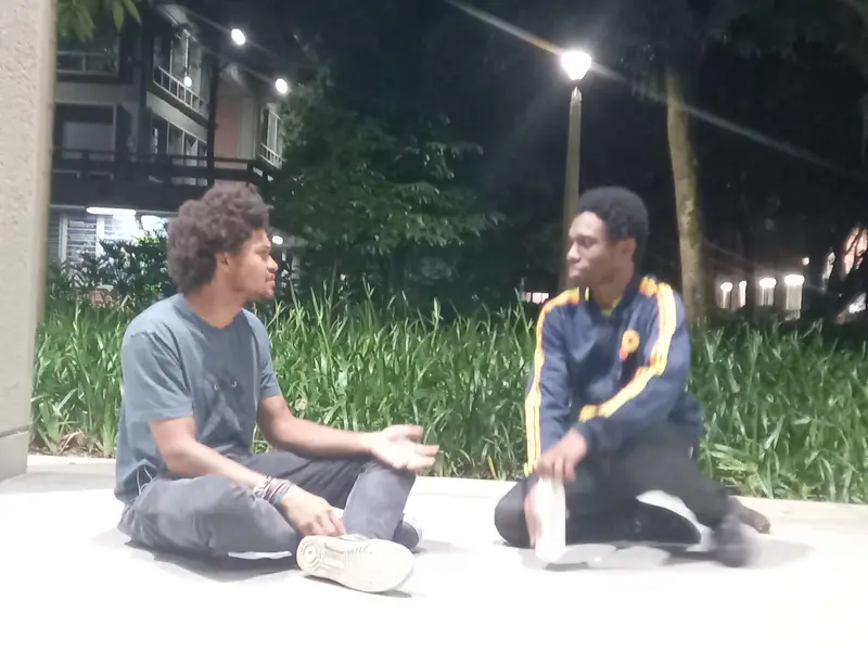 Dos integrantes sentados en el piso conversan en una improvisación nocturna