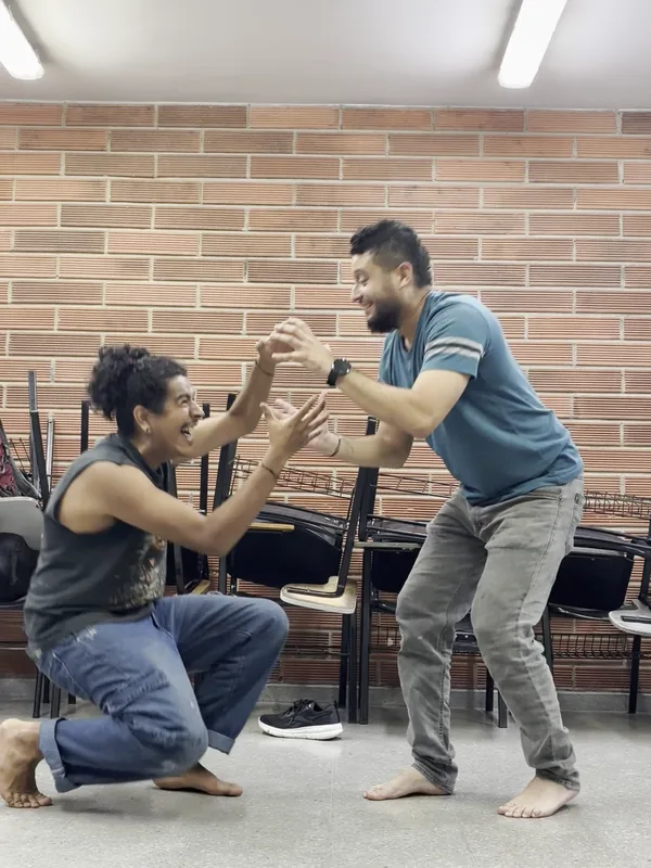 Dos integrantes improvisan frente a frente, uno arrodillado con las manos abiertas