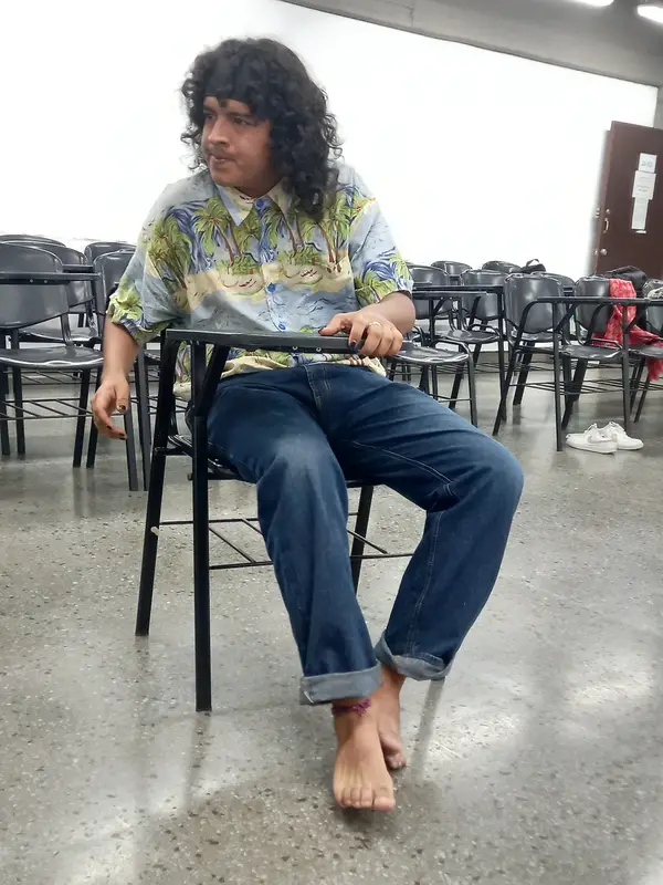 Un integrante sentado en una silla, descalzo, construye su personaje