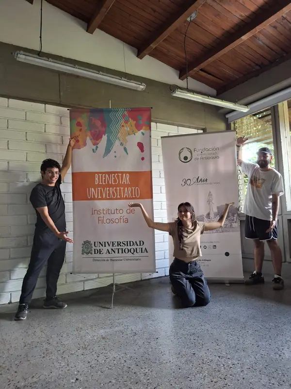 Tres fundadores posan junto a los pendones de Bienestar Universitario y la Fundación UdeA